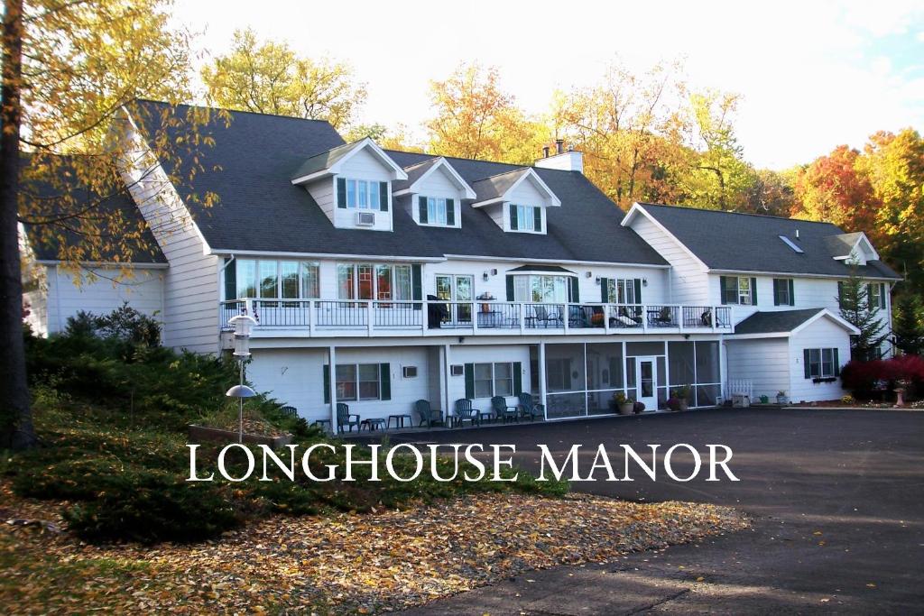 uma grande casa branca com o sinal para a mansão Longmire em Longhouse Manor B&B em Watkins Glen