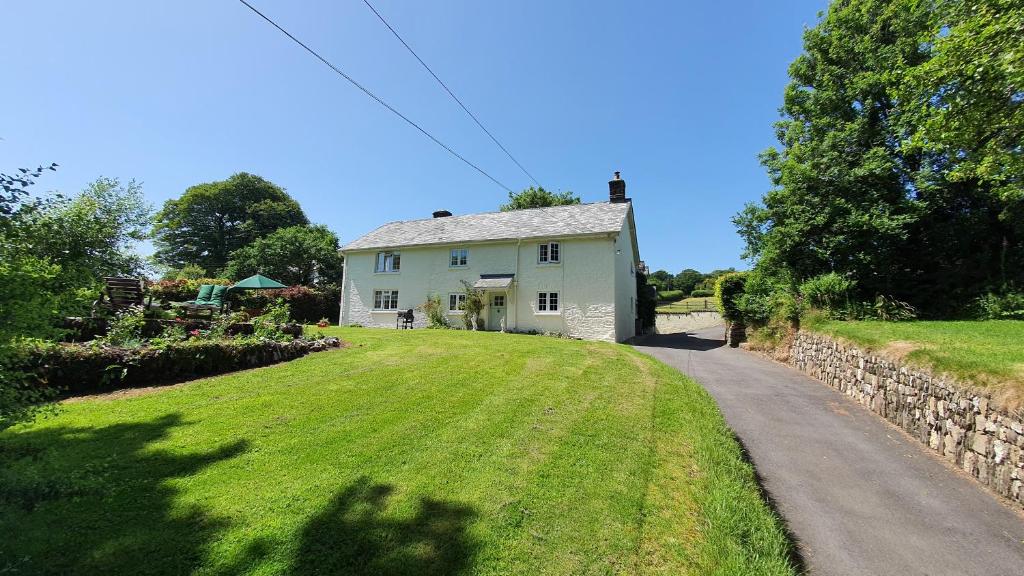 a white house with a stone wall and a road at Wey House in Withypool