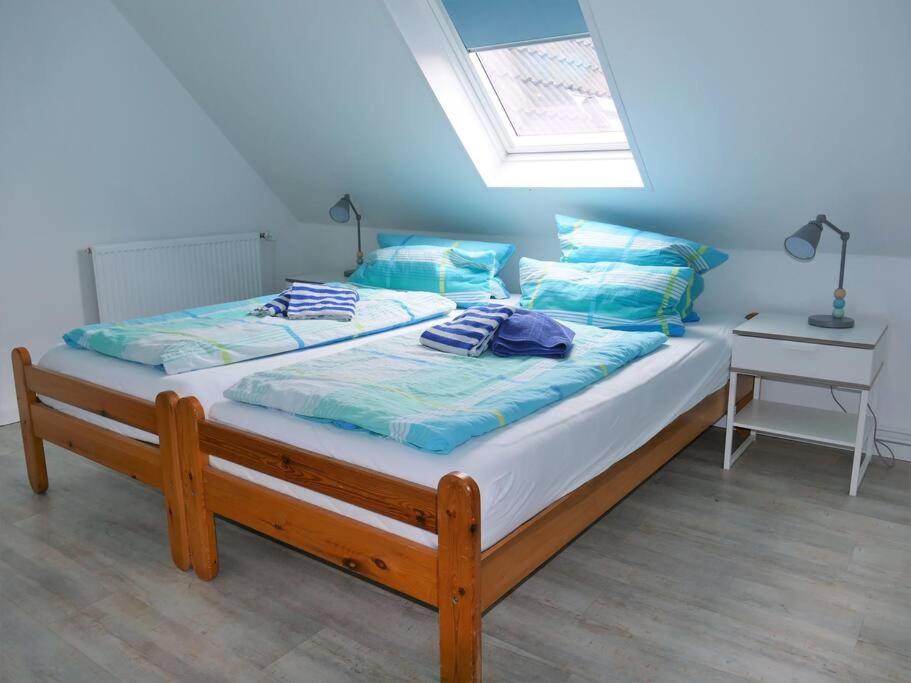 Un dormitorio con una cama con almohadas azules y una ventana en Ferienwohnung: Utkiek en Langeoog