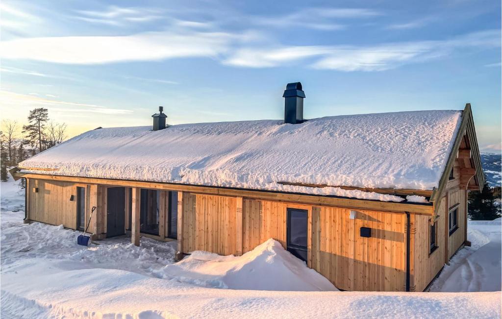 uma casa de madeira com neve no telhado em Awesome Home In yer With Kitchen em Hafjell