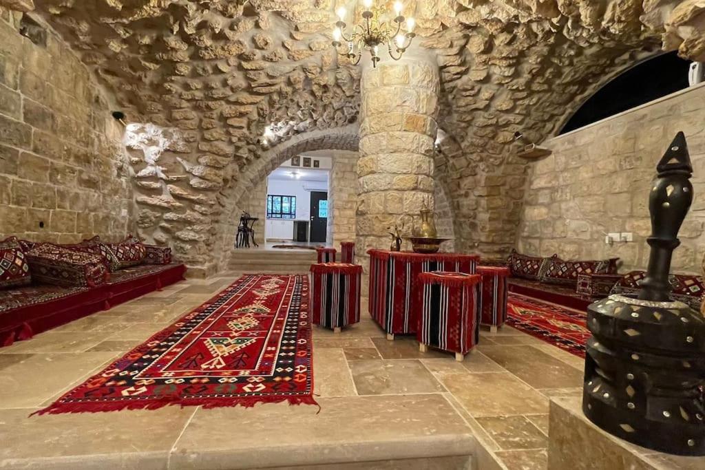 a large room with a stone building with red carpet at Palace of Sultan Jalal Basha in Abū Ghaush