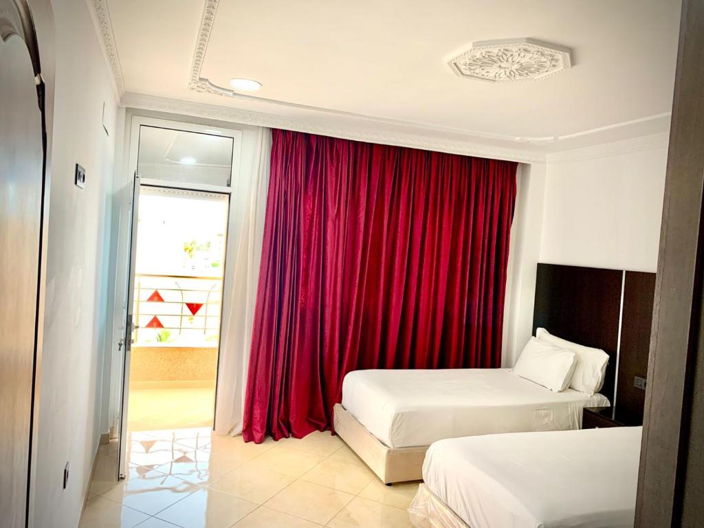 ein Hotelzimmer mit 2 Betten und einem roten Vorhang in der Unterkunft HOTEL BEAUTIFUL in Nador