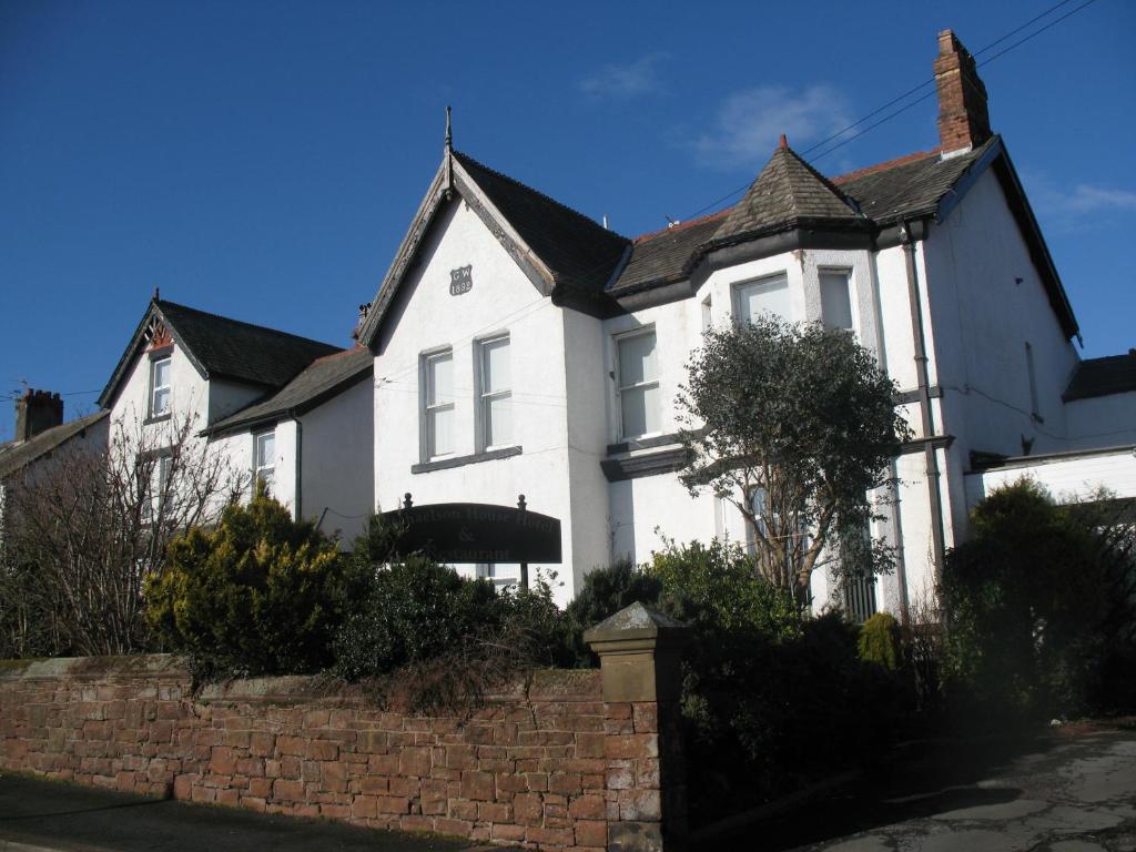 a white house with a brick fence in front of it at Michaelson House Hotel in Barrow in Furness