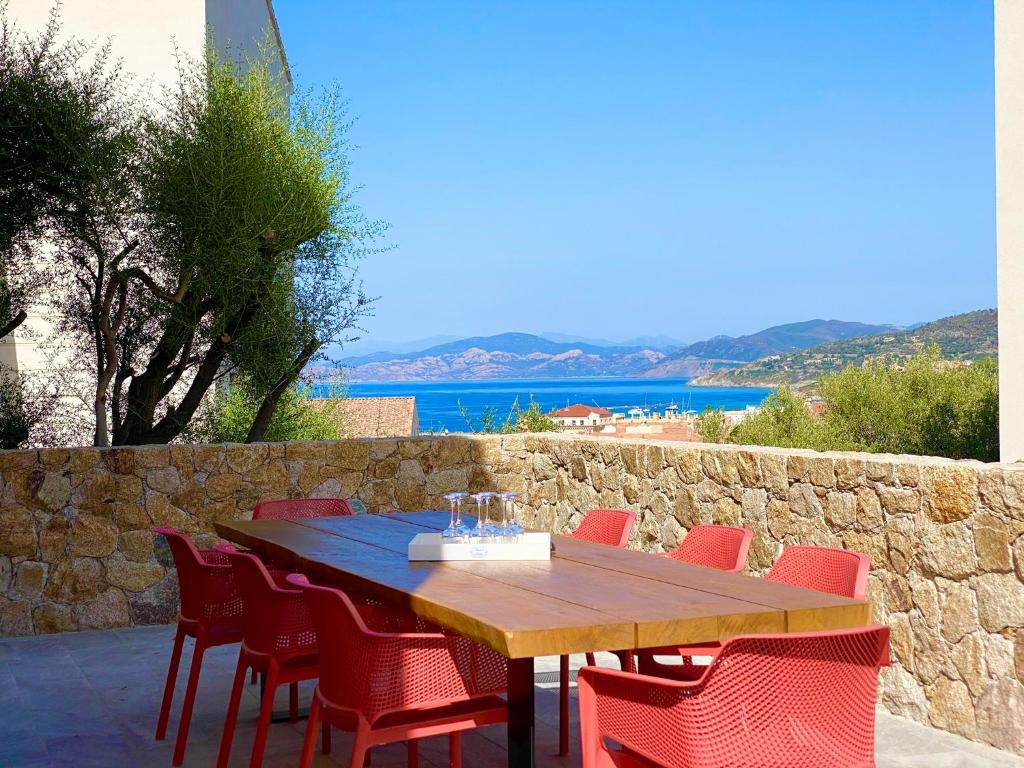 a wooden table with red chairs and a stone wall at Casa u fornu Residence & Spa in LʼÎle-Rousse