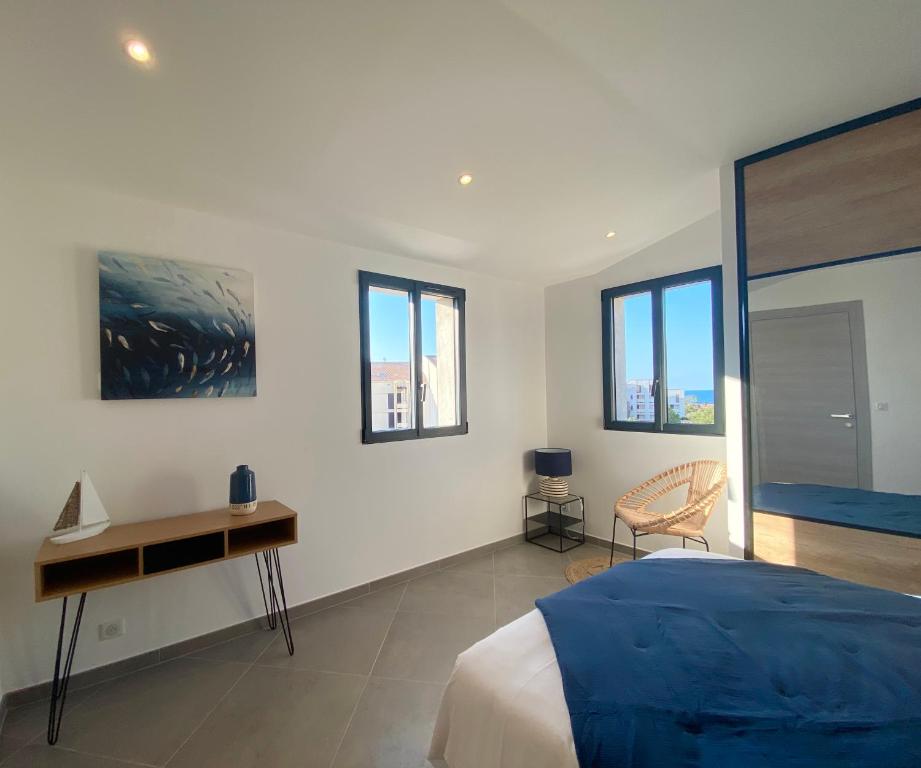 Schlafzimmer mit einem Bett, einem Schreibtisch und Fenstern in der Unterkunft Casa u fornu Residence & Spa in LʼÎle-Rousse