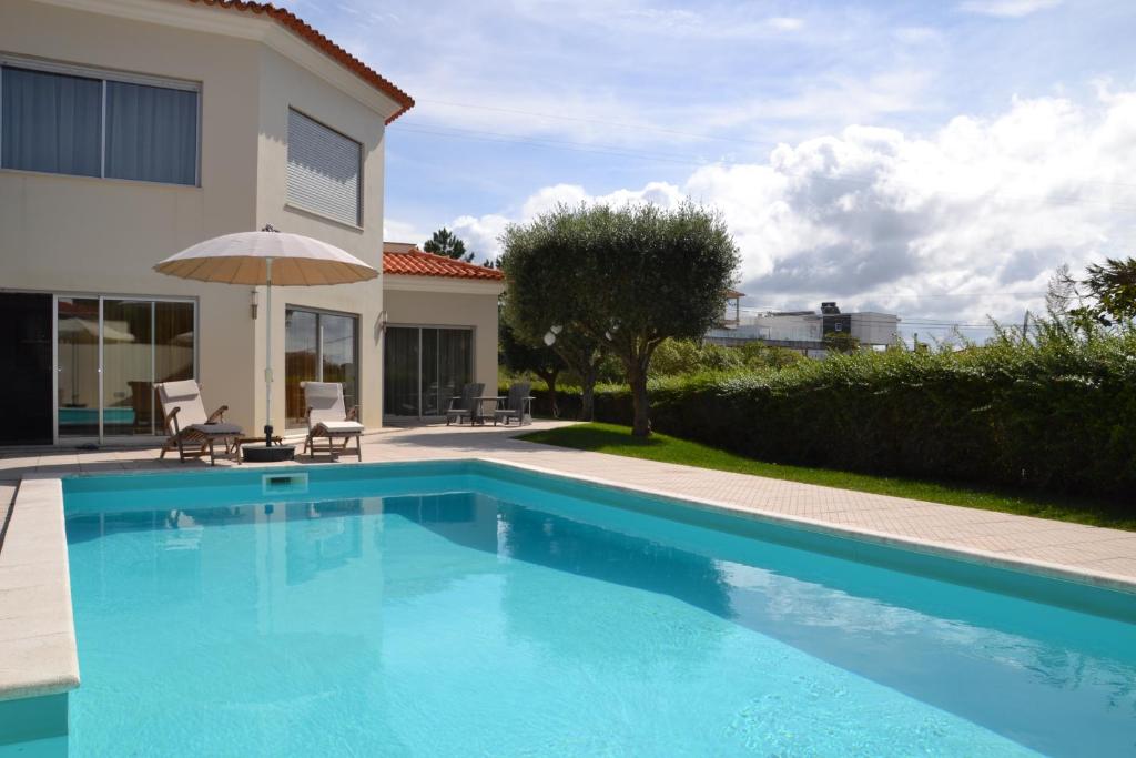 a large blue swimming pool next to a house at Casas Cerejas in Serra de Mangues