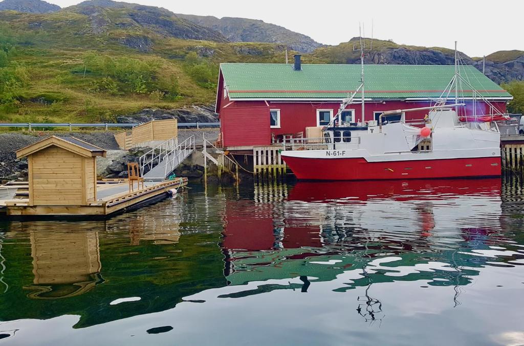 una casa rossa e una barca in un corpo d'acqua di Fishermans Rorbu 2 - Lofoten a Ramberg