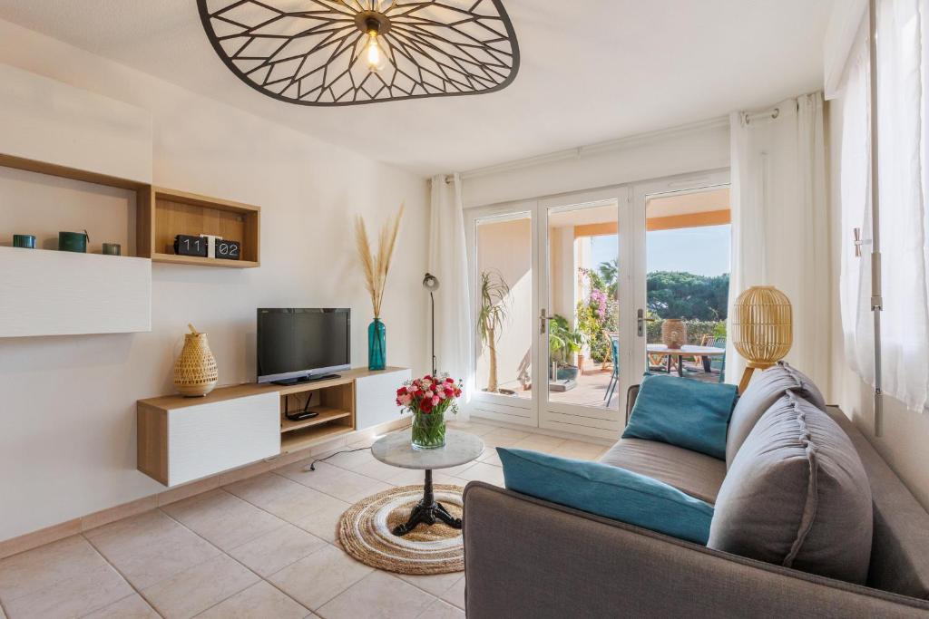 un salon avec un canapé et une télévision dans l'établissement Appartement avec jardin, clim & piscine - Proche plages et randos, parking privé - La Girelle, à Hyères