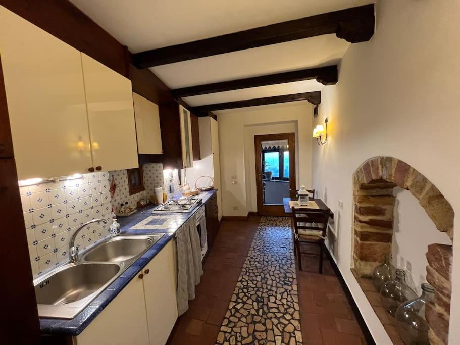 Casa Porta Fontevecchia panoramica في سبيلّو: مطبخ مع مغسلتين ومدفأة حجرية
