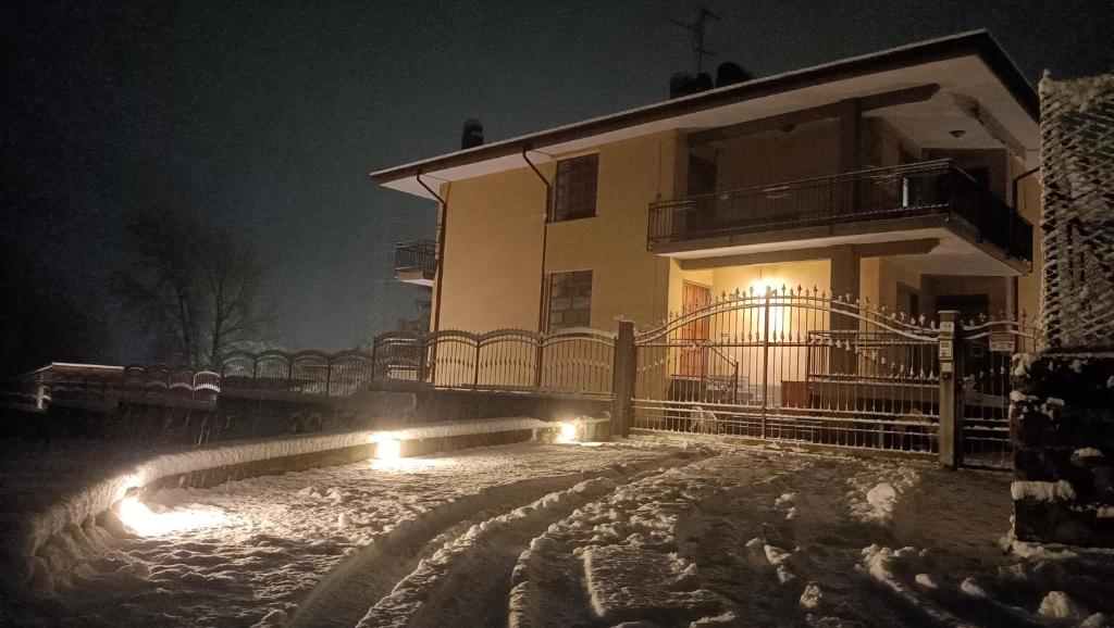 dom ze światłami w śniegu w nocy w obiekcie Champdepraz Casa Vacanze w mieście Champdepraz