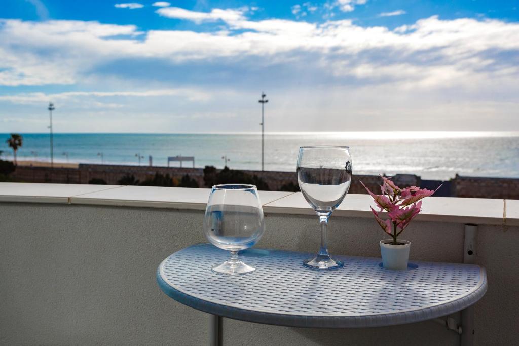 dos copas de vino en una mesa con vistas al océano en POSEIDON Beach Apartment & parking by Cadiz4Rentals, en Cádiz