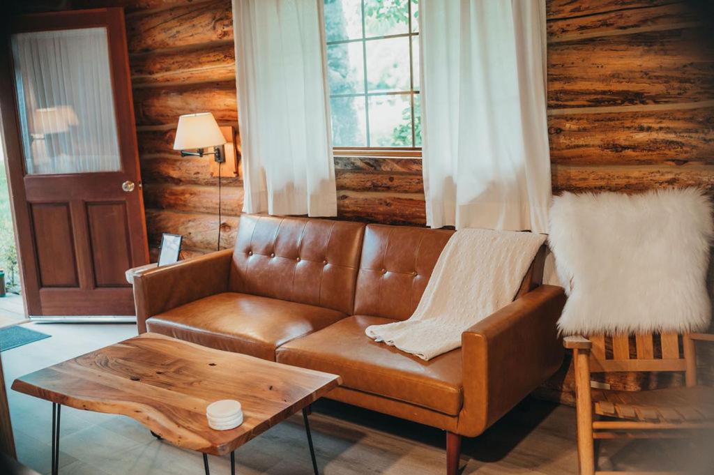 a living room with a leather couch and a table at Wilder and Pine Riverside Cabins in Stevenson