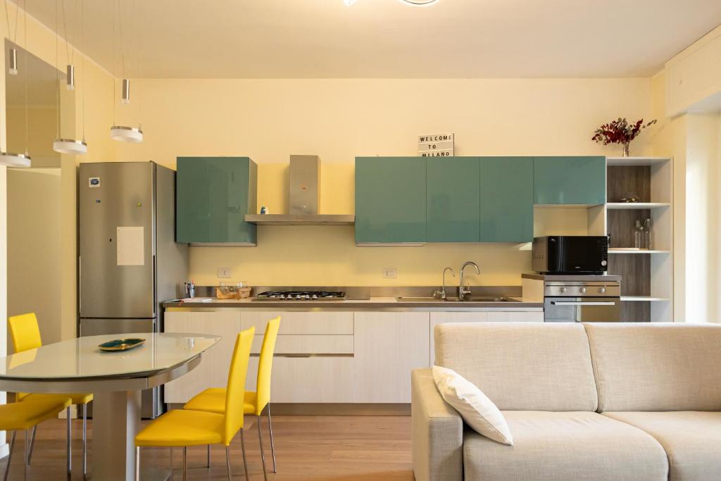 een keuken met groene kasten en een tafel en een bank bij Bilocale Moderno ed Esclusivo in Milaan
