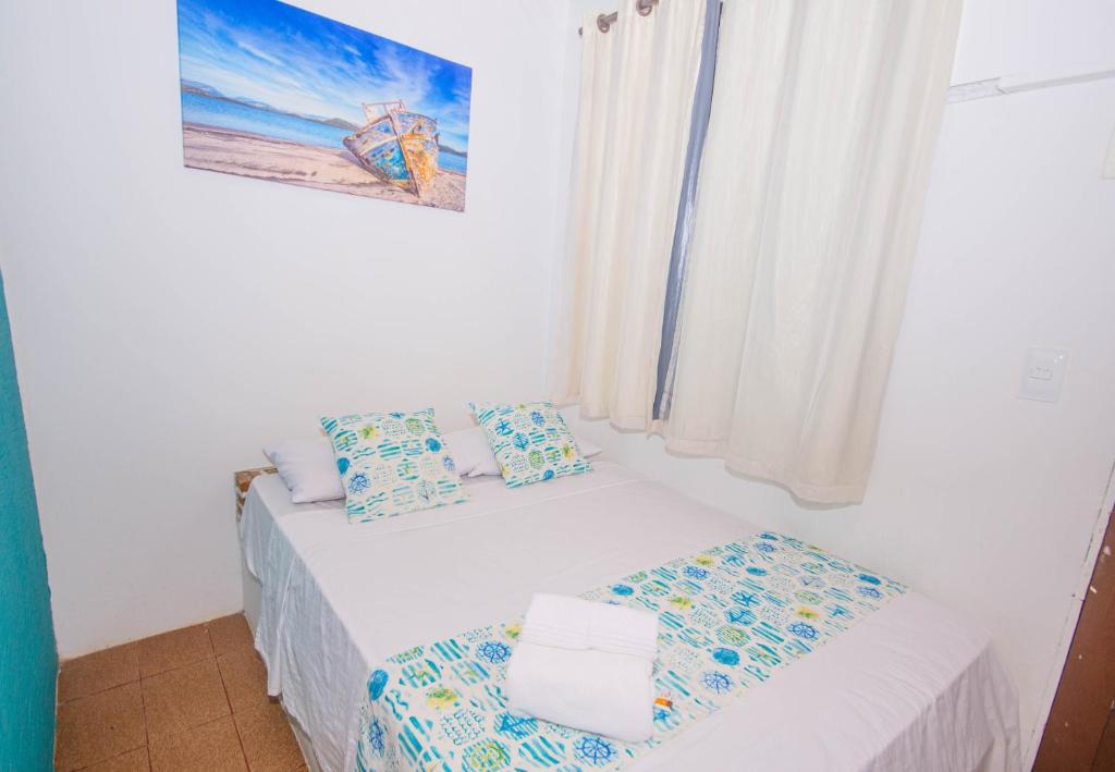 a small white bedroom with a bed and a window at Pousada Natal in Morro de São Paulo