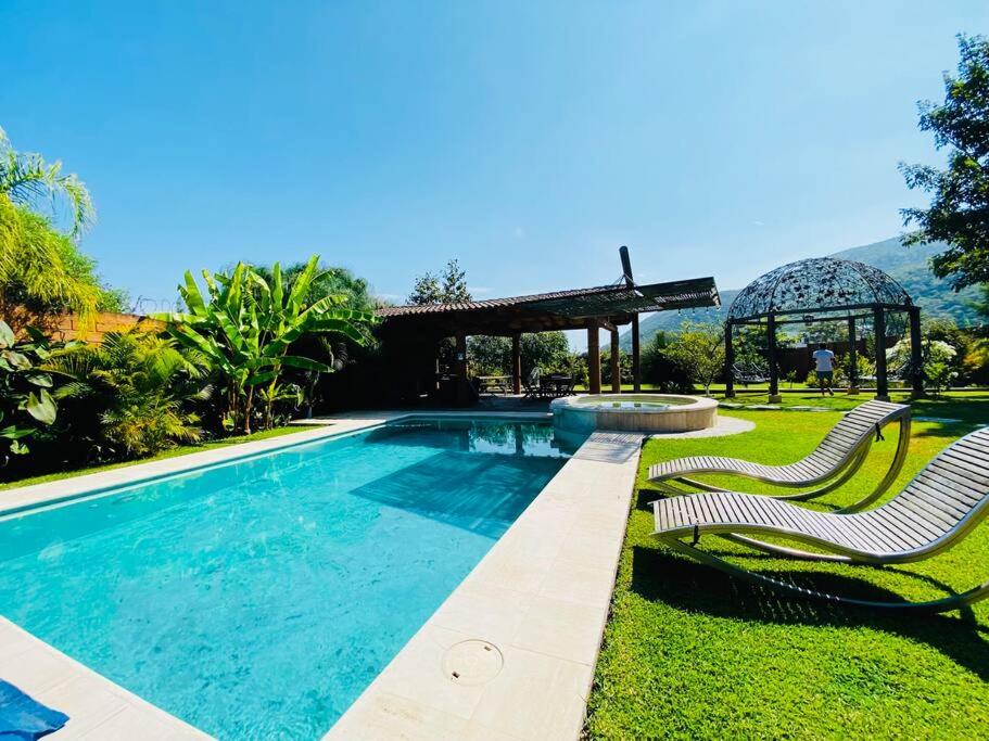 een zwembad met 2 stoelen en een prieel bij La Casa del Lago in Malinalco