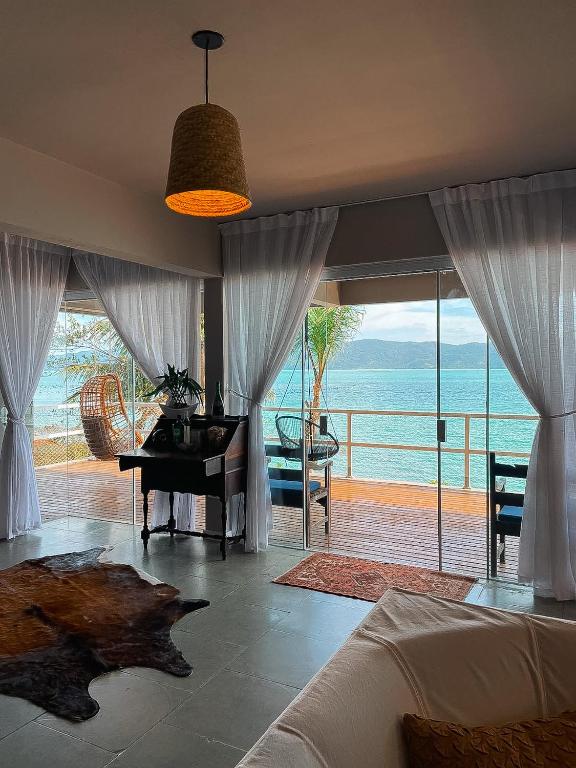 a bedroom with a piano and a view of the ocean at Casa pé na areia para até 14 pessoas em bombinhas in Bombinhas