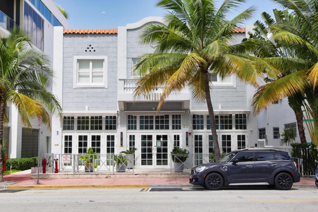 een auto geparkeerd voor een gebouw met palmbomen bij The Julia Hotel in Miami Beach