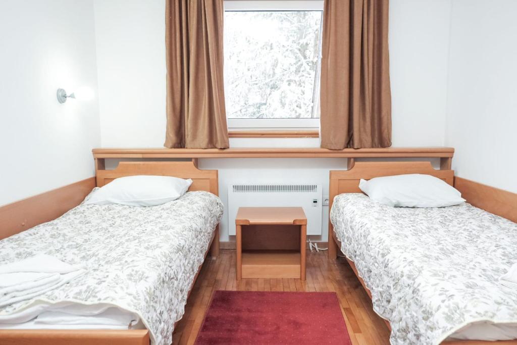 two beds in a room with a window at Apartman Sakovic in Kopaonik