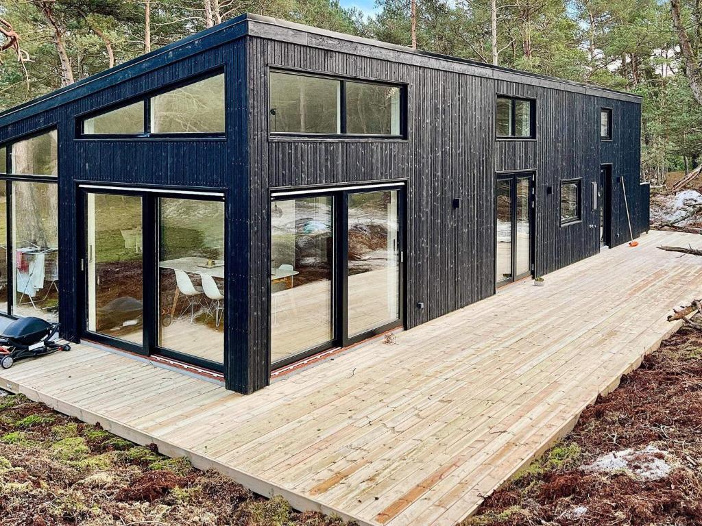 a black modular house with a wooden deck at Holiday home Nexø XLI in Vester Sømarken