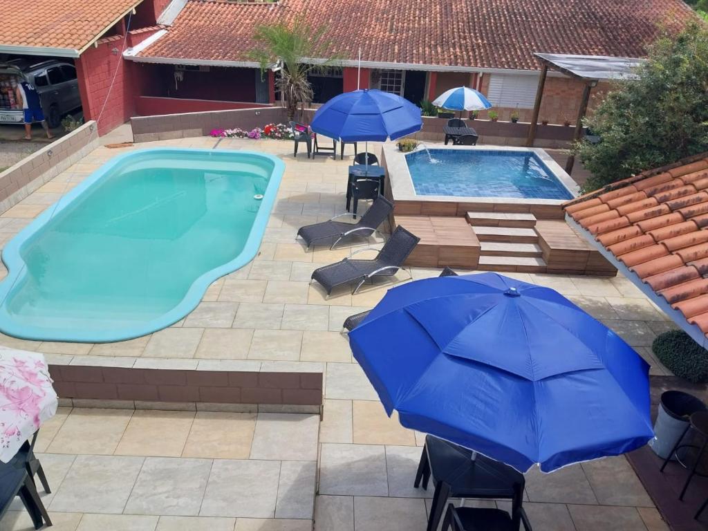 a swimming pool with two umbrellas and a pool at Pousada Beija flor in Extrema