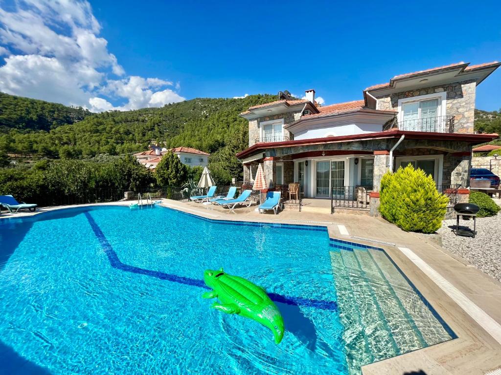 a swimming pool in front of a house with a dolphin in the water at 4 Bedroom - 3 Bathroom - 8 Person, Private Pool - Private 1000m2 Garden, DETACHED Villas, Unlimited WiFi - Free Parking in Fethiye