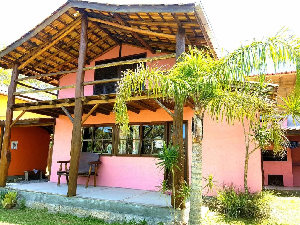 Casa rosa con pérgola de madera en Rosatrip Surf Bungalows, en Praia do Rosa