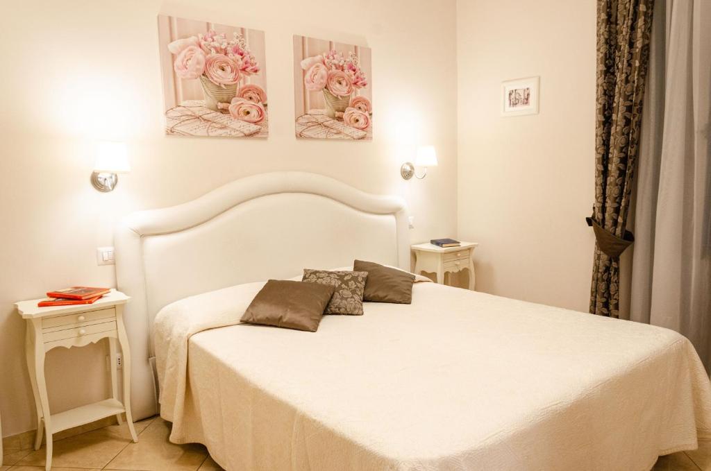 タオルミーナにあるTaormina B&Bの白いベッドと壁に3つの絵画が飾られたベッドルーム1室