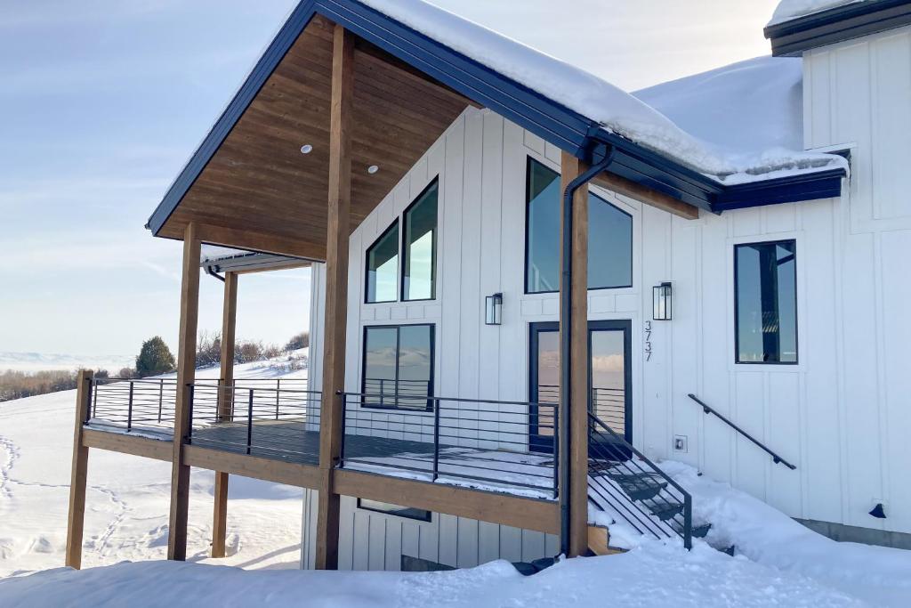 a house with a deck in the snow at The Belle of Bear Lake in Fish Haven
