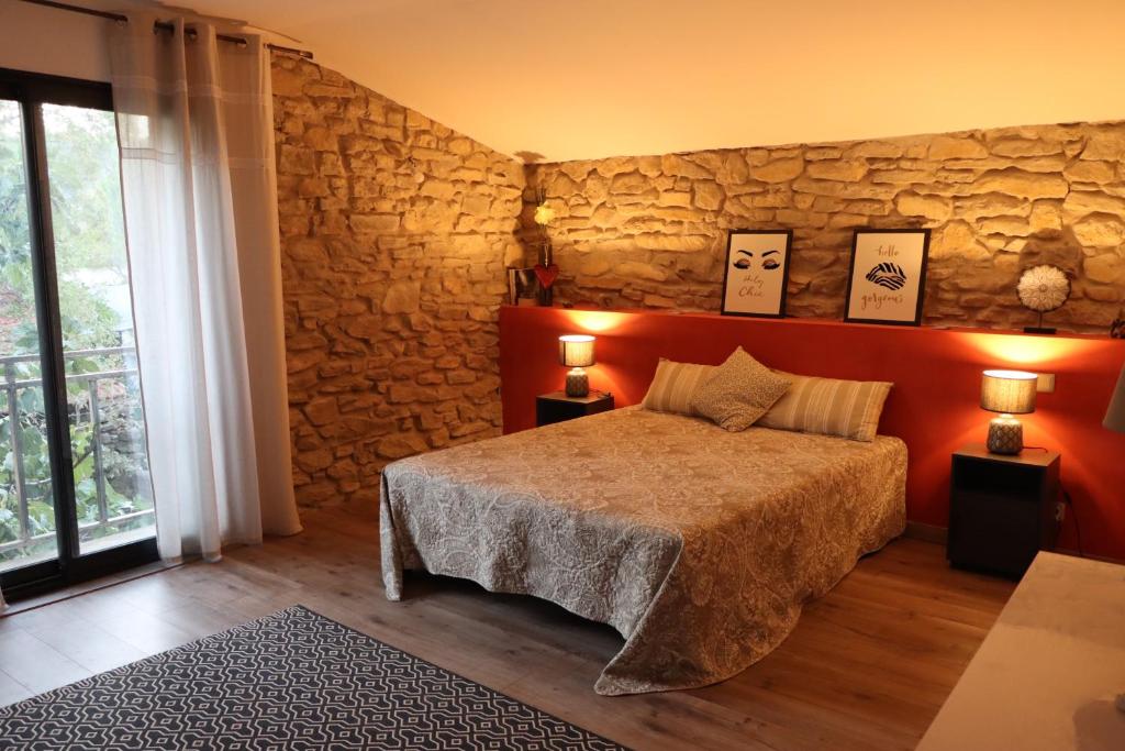 um quarto com uma cama e uma parede de pedra em Au Paradis des 2 Petites Abeilles em Félines-Minervois