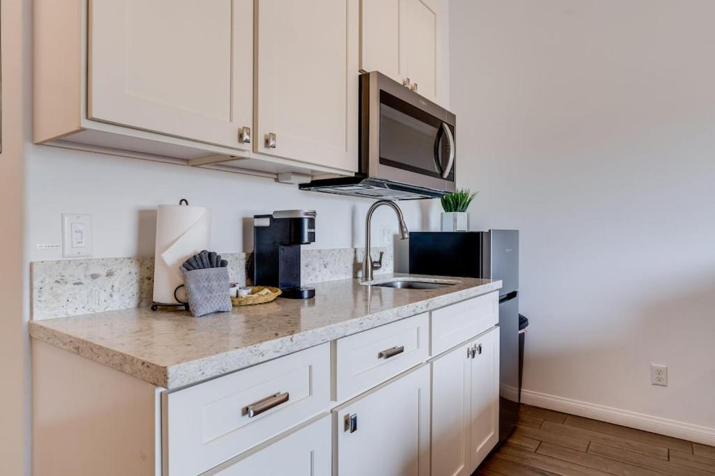 a kitchen with white cabinets and a sink and a microwave at Unit 2 Maui Ohana Modern Studio in Wailuku
