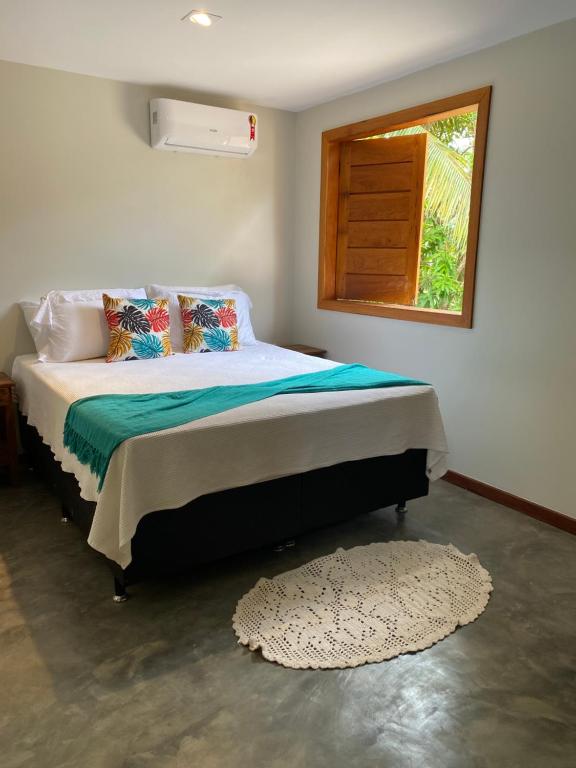 a bedroom with a bed with a window and a rug at Flat com piscina e perto do mar Taipus in Marau
