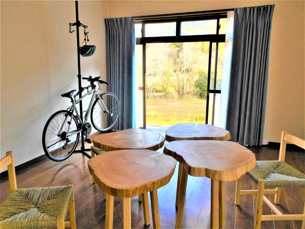 una stanza con quattro tavoli in legno e una bicicletta di ゲストハウスみちしお 