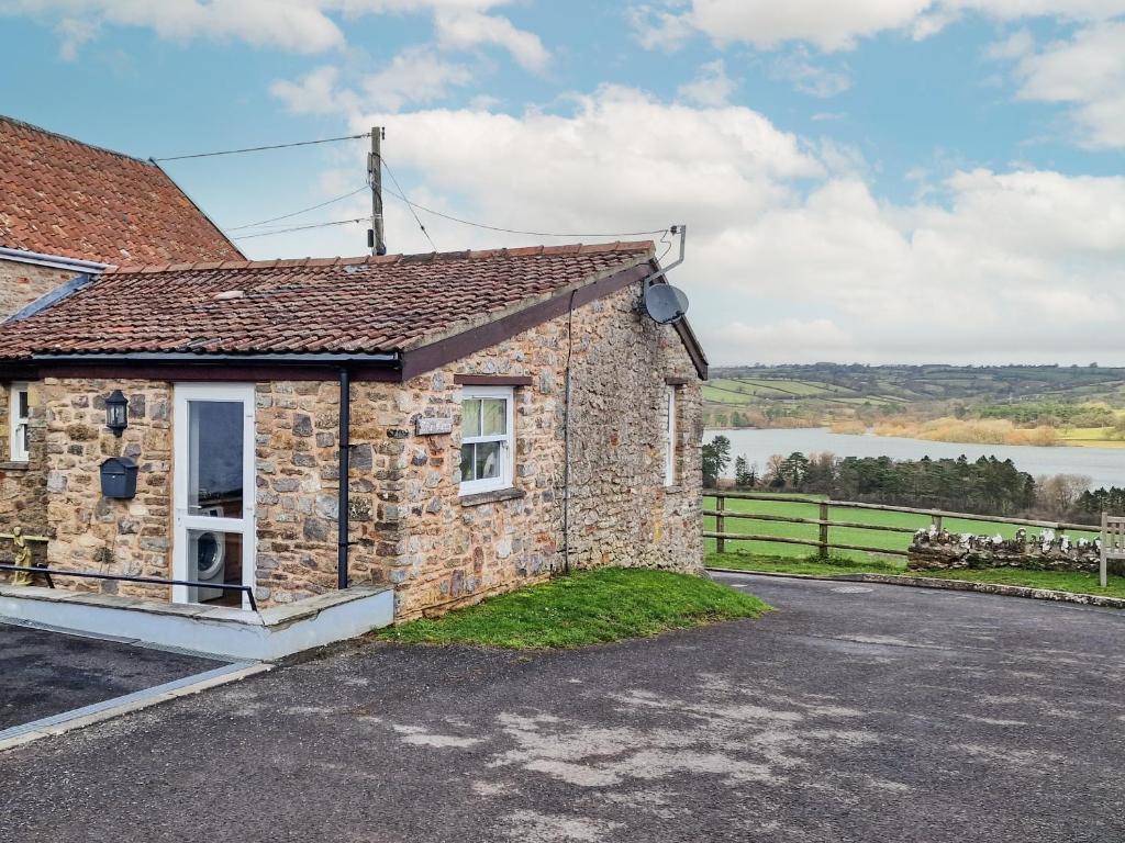 a stone cottage with a view of a lake at The Barn in Blagdon