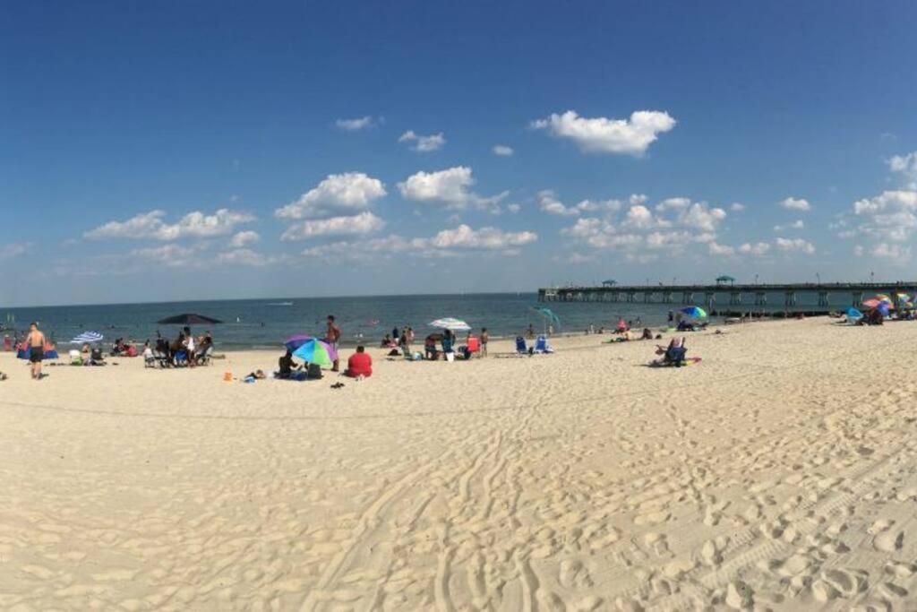 un groupe de personnes sur une plage avec parasols dans l'établissement Petit n Cozy Beach Bungalow 5min walk to the beach, à Hampton