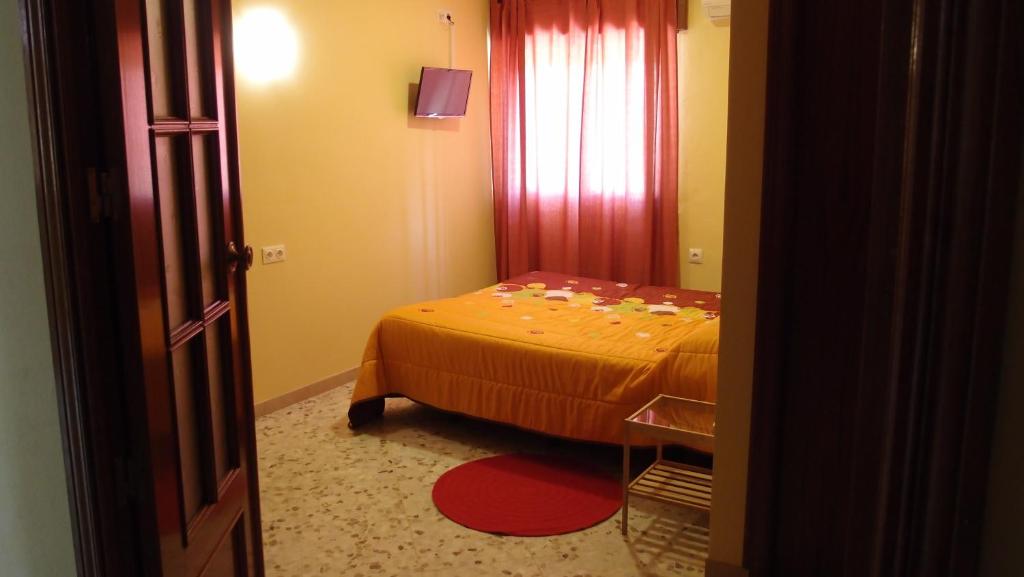 a bedroom with a bed and a red curtain at Hotel Catalán Puerto Real in Puerto Real