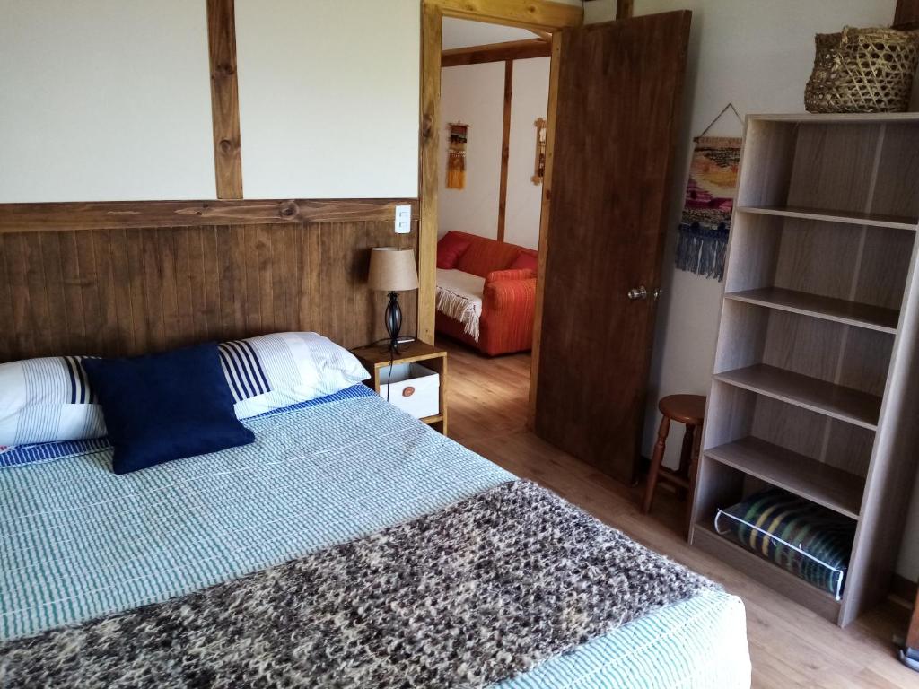 1 dormitorio con 1 cama con cabecero de madera en Cabañas Rincón de Ten Ten, en Castro