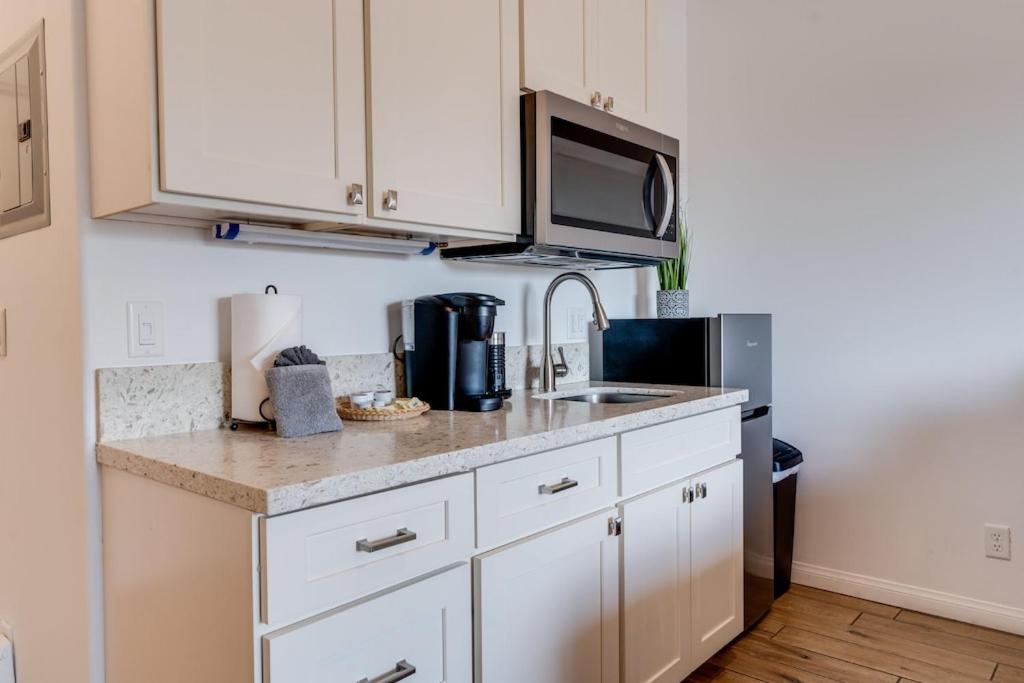 a kitchen with white cabinets and a sink and a microwave at Unit 4 Maui Ohana Modern Studio in Wailuku