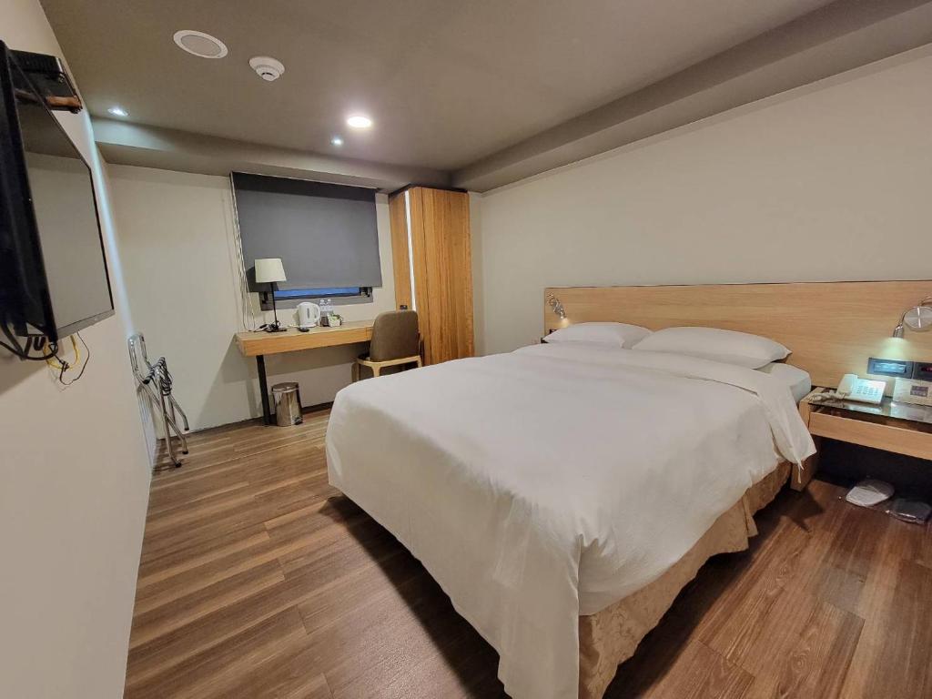 a bedroom with a large bed and a flat screen tv at Simple + Hotel in Taipei