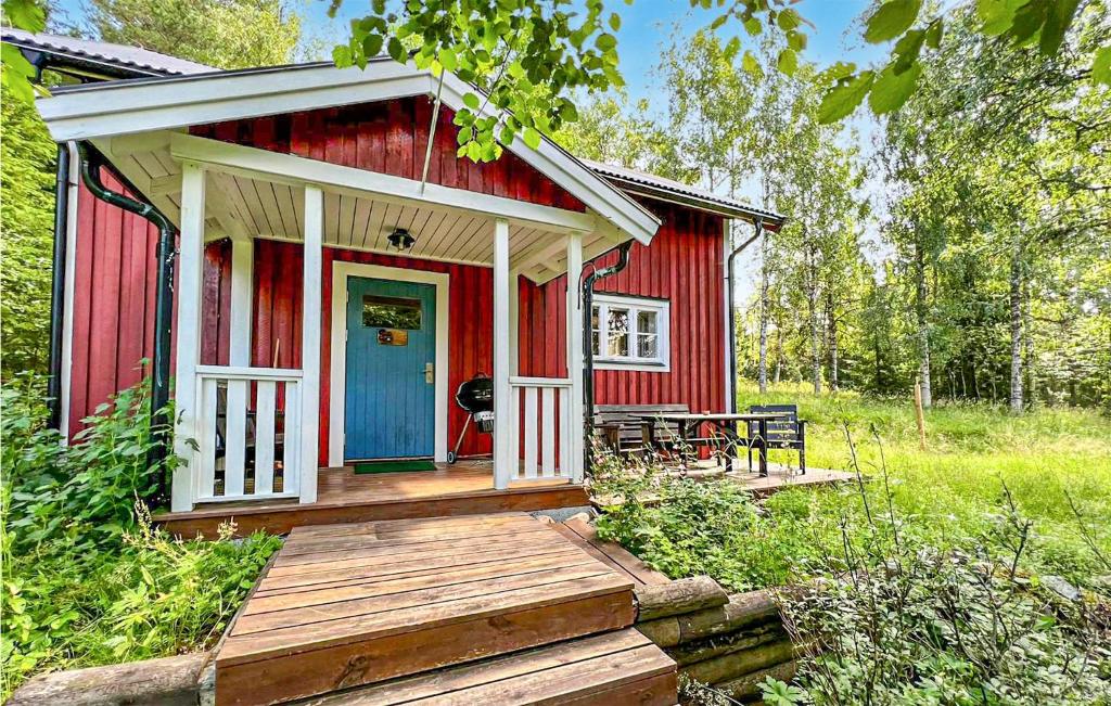 um chalé vermelho com um alpendre em madeira e uma porta azul em Nice Home In Letafors With Kitchen em Letafors