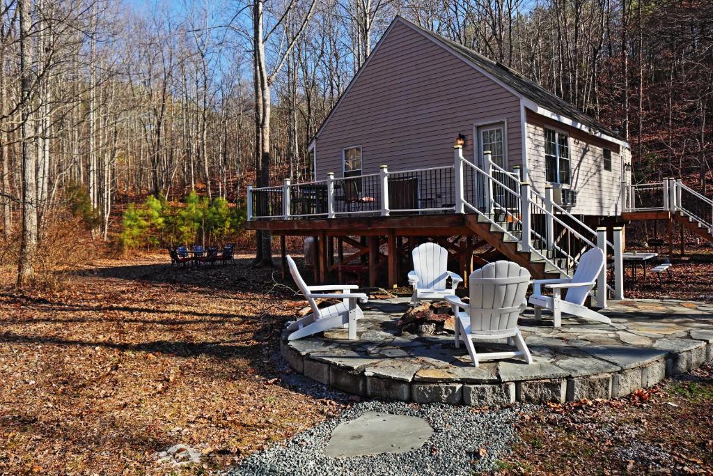 a house with a deck and two chairs and a dog sitting on a patio at Our Private Wooded Cabin in Chatham
