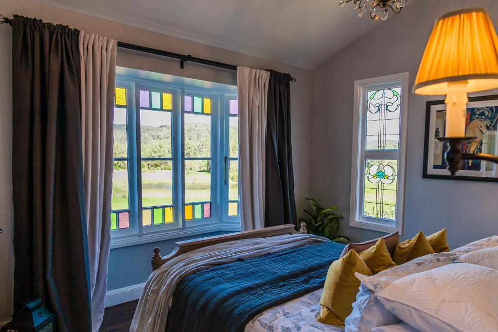 a bedroom with a bed and two windows at Wollombi Wines in Wollombi