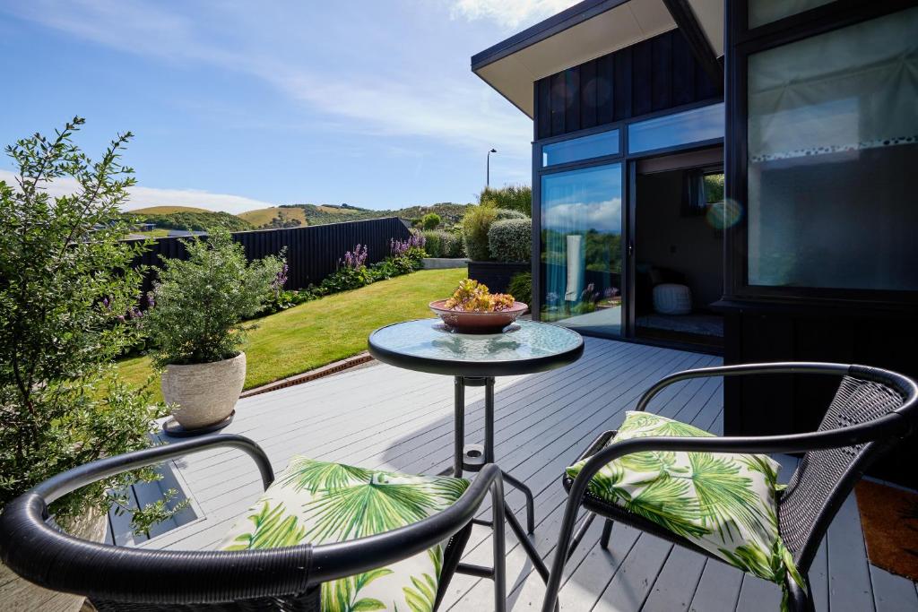 a patio with two chairs and a table on a deck at Golfer's Retreat in Kaikoura