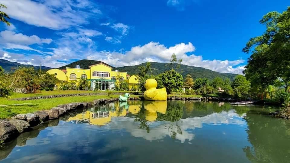 a river with a yellow house in the background at 依比鴨鴨水岸會館 Ducking House in Ruisui