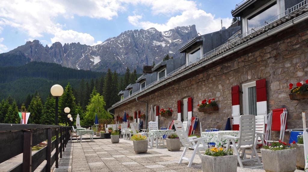 a building with chairs and tables and mountains in the background at Residence Chris Appart in Carezza al Lago
