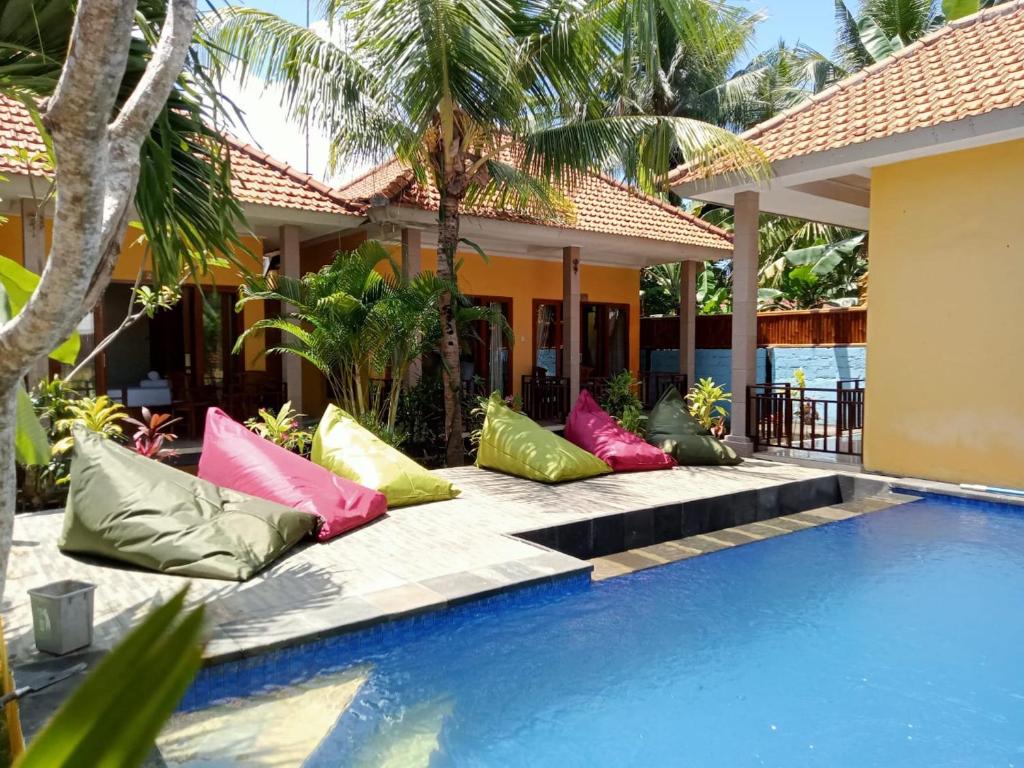 a row of colorful pillows sitting next to a swimming pool at Yellow Bridge Guest House in Nusa Lembongan