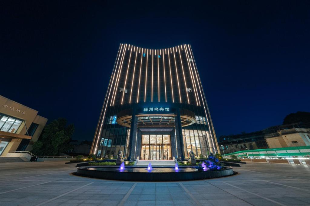 a building with a fountain in front of it at night at White Swan Guest House MeiZhou in Meizhou