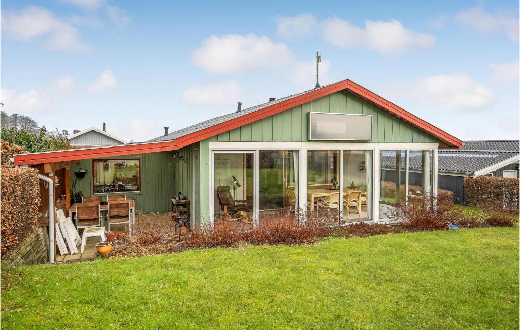ein grünes Haus mit großen Fenstern und einem Hof in der Unterkunft 3 Bedroom Lovely Home In Bjert in Binderup Strand