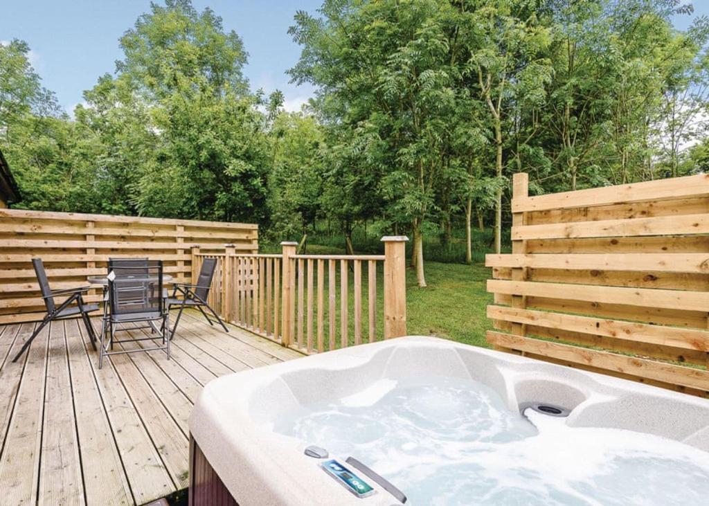 a hot tub on a deck with a table and chairs at Meadows End Lodges in Cartmel