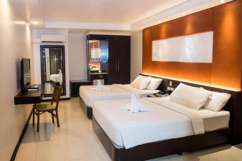 a hotel room with two beds and a desk at M Citi Suites in Cebu City