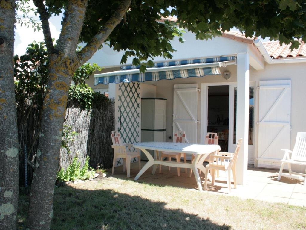 um pátio com uma mesa e cadeiras em frente a uma casa em Maison La Tranche-sur-Mer, 3 pièces, 4 personnes - FR-1-22-209 em La Tranche-sur-Mer